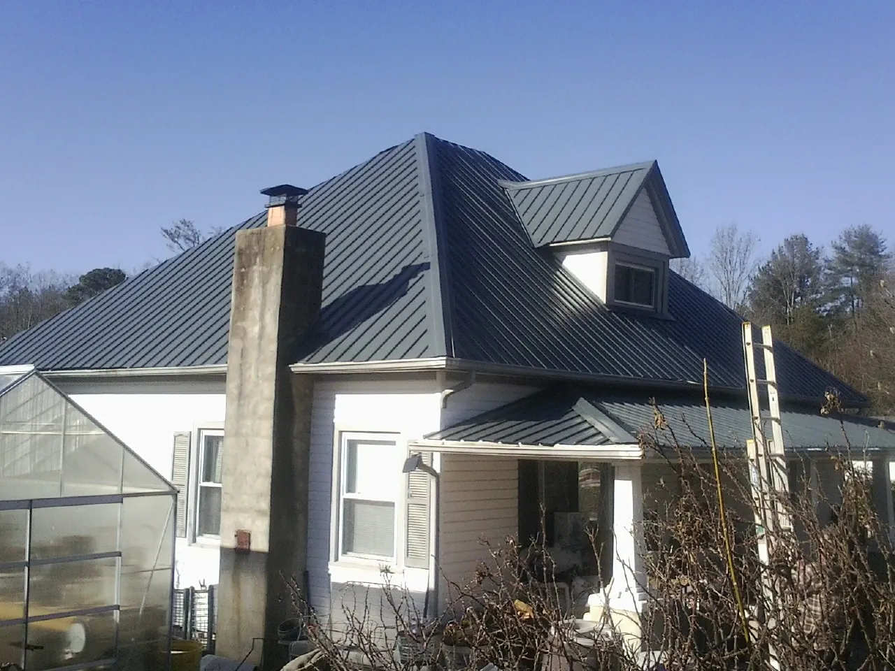 Dark blue standing seam metal roof on a white farmhouse with dormer — Slate & Tile Roof Repair by Roofing Brothers in China