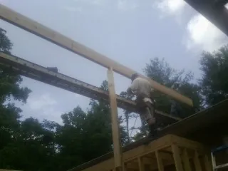 Carpenter setting a ridge beam over a new addition frame — Ice Dam Removal by Roofing Brothers in China