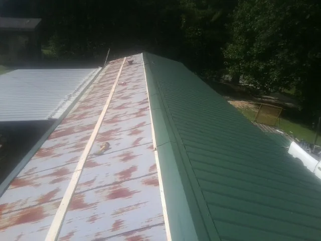 Old rusted panels beside newly installed green metal roofing — Wind Damage Roof Repair by Roofing Brothers in China