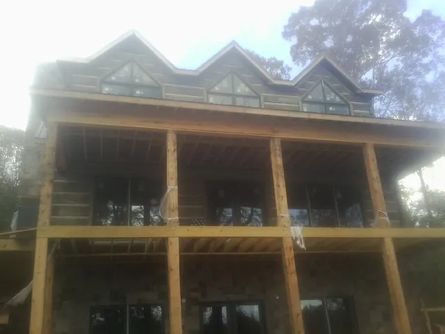 Dormers and porch framing on a large log home under construction — Roof Coating work by our crew in China