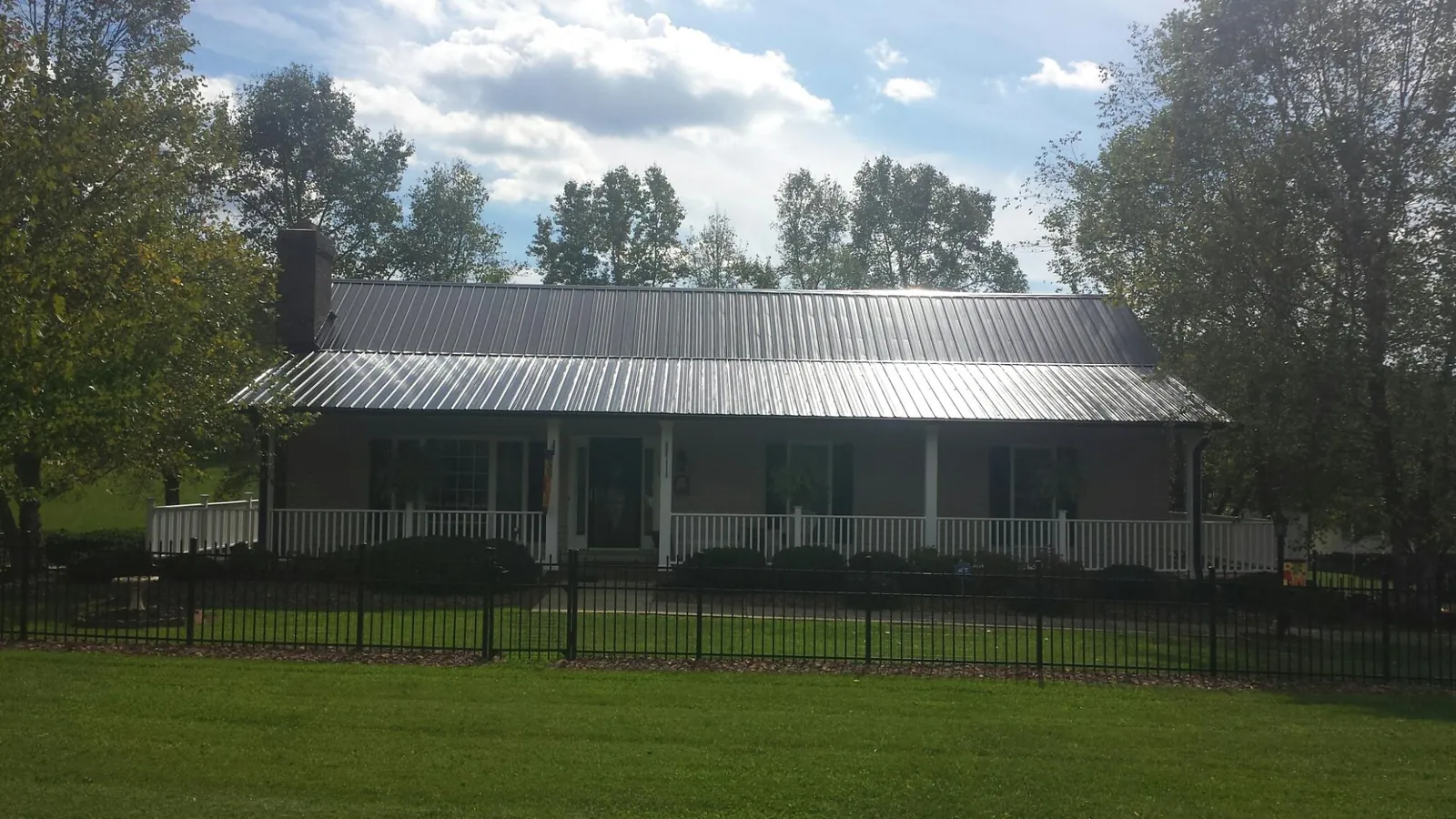 Gray metal roof on a brick ranch with a full width front porch — Gutter Guard Installation work by our crew in China