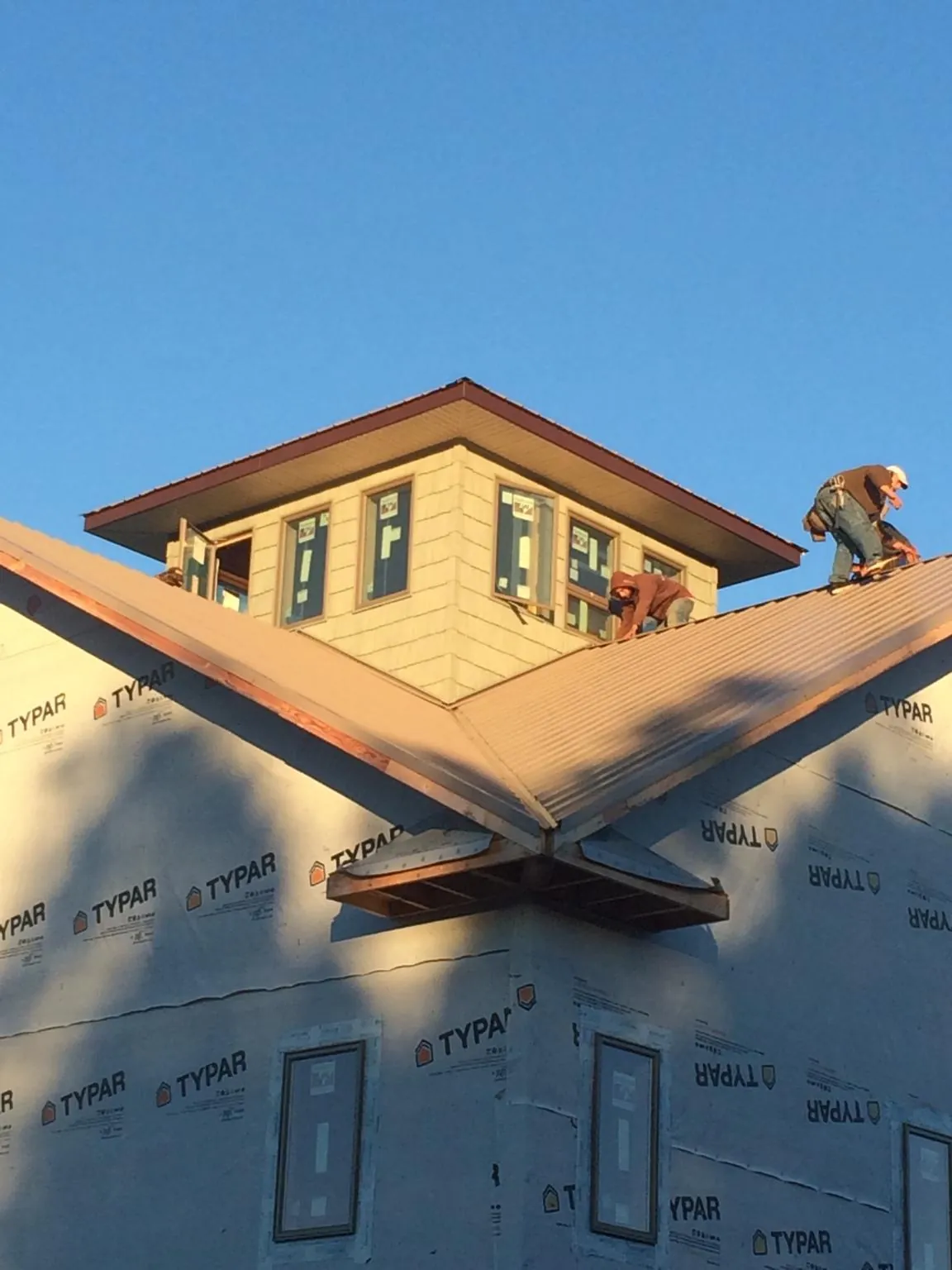 Roofers working around a rooftop cupola on a new metal roof at sunset — Roof Waterproofing in China by Roofing Brothers